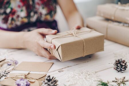 Close up of hands woman present gift box on wooden table with xmas decoration.の写真素材