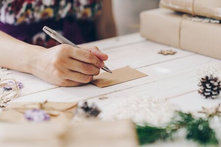 Close up of hands woman writing empty wishlist and christmas card on wooden table with xmas decoration.の写真素材