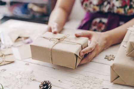 Close up of hands woman present gift box on wooden table with xmas decoration.の写真素材