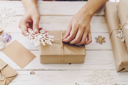 Close up of hands holding wrapping gift box on wooden table with xmas decoration.の写真素材