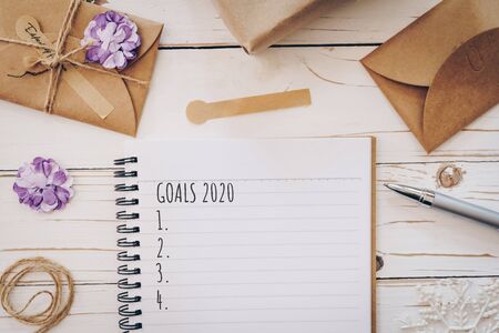 Top view of New Year Goals 2020 list empty note pad and christmas card on wooden table with xmas decoration.の写真素材