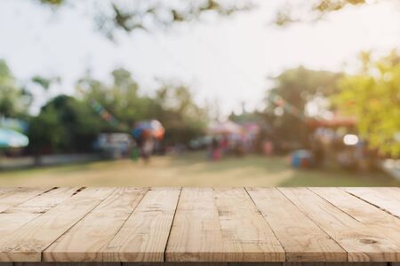 Empty wood table and defocused bokeh and blur background of garden trees in sunlight, display montage for product.の写真素材