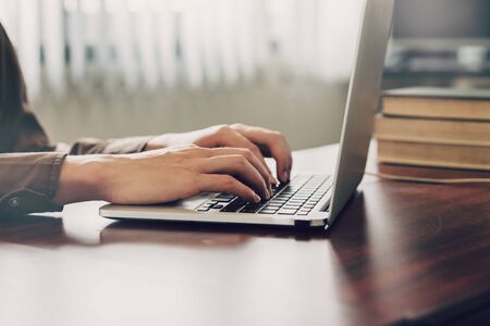 business man hand texting laptop on wooden tableの写真素材