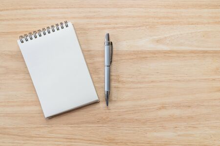 Top view of blank notebook with pen and natural light on wooden table.の写真素材
