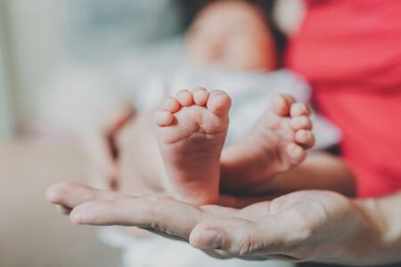 Feet of a newborn baby in the hands of mother.の写真素材