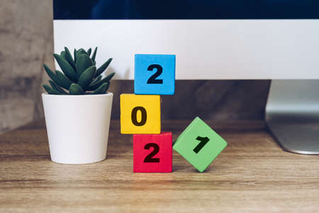 2021 happy new year on wood block on wood table desktop computer and pot plant. new year conceptの写真素材