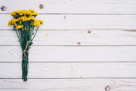 Yellow flowers of bouquet, top view on white wooden background texture with copy spaceの写真素材