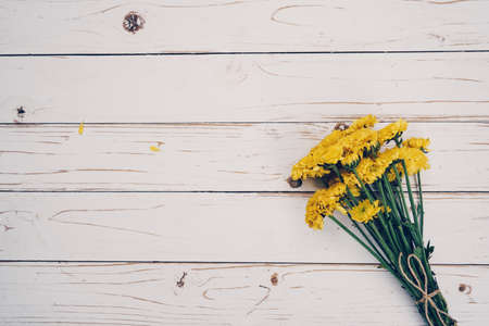 Yellow flowers of bouquet, top view on white wooden background texture with copy spaceの写真素材