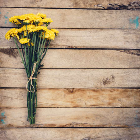 Yellow flowers of bouquet, top view on wooden background texture with copy spaceの写真素材