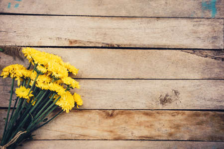 Yellow flowers of bouquet, top view on wooden background texture with copy spaceの写真素材