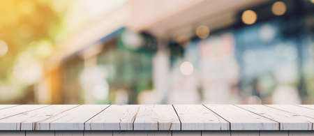 Empty wood table and blurred light table in coffee shop and cafe with bokeh background. product display template.の写真素材