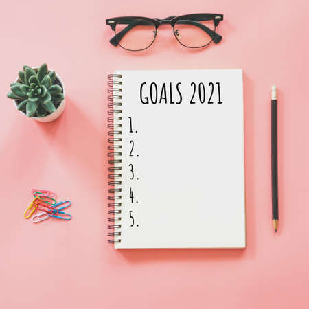 2021 New year concept. Goals list in notepad, smartphone, stationery on pink pastel color with copy spaceの写真素材