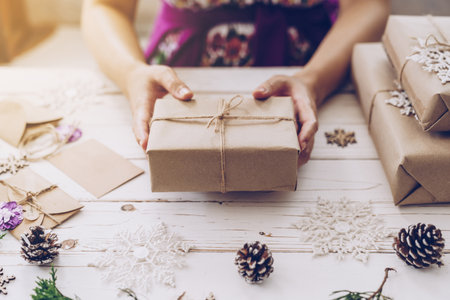 Woman hand holding beautiful Christmas gift box at tableの写真素材