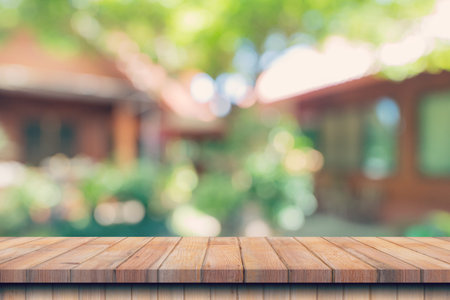 Empty wood table and defocused bokeh and blur background of garden trees with sunlight. product...
