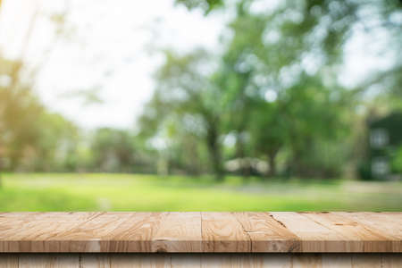 Empty wood table and defocused bokeh and blur background of garden trees with sunlight. product display template.の写真素材