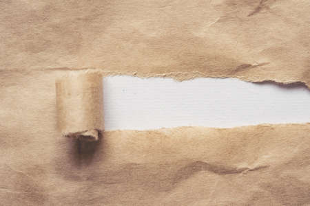 Brown paper torn to reveal white panel for text with copy spaceの写真素材