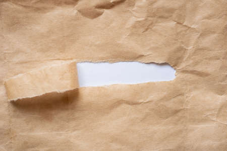 Brown paper torn to reveal white panel for text with copy spaceの写真素材