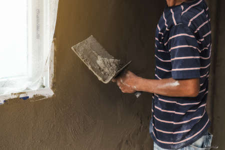 worker man's hand plastering a wall with trowelの写真素材