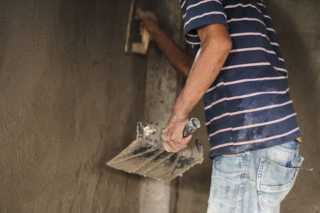 worker man's hand plastering a wall with trowelの写真素材