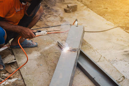 Man welder doing a metal staircase structure in a residential building using a welding machine.の写真素材
