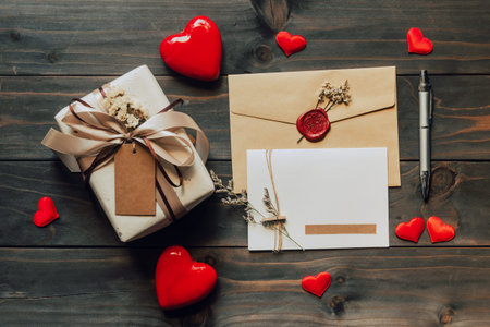 Gift box and greeting card with bow ribbon and paper hearts on wooden table for Valentines day. copy...