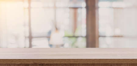 Wooden table top with blurred people in coffee shop and cafe background for display montage, copy space.の写真素材