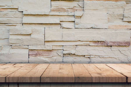 Empty wood table and pattern of decorative slate stone wall surface with copy spaceの写真素材