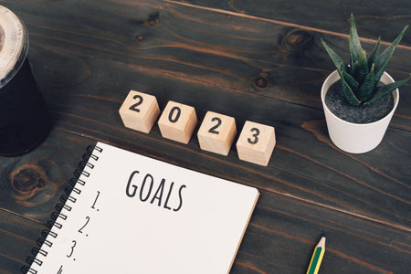 2023 goals text on notepad with coffee cup and pen on wooden deskの写真素材