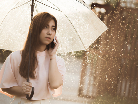 Asian woman she was on the phone in the rain alone.の写真素材