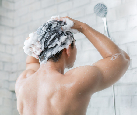 The man is washing his hair, he use shampoo.の写真素材