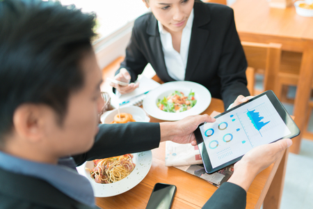 Asian business break for lunch at a restaurant.He was watching the stock market at the table.の写真素材
