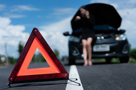Asian woman's car  broken.She is waiting for someone to help.の写真素材