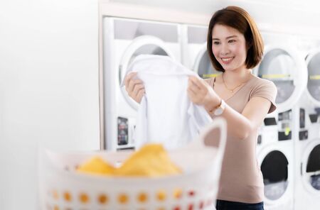 Asian women looking at shirts that are washed from the laundry shopの写真素材