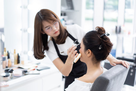 Asian beautician doing makeup for customer.