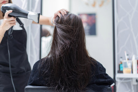 hairstylist doing hair for customer in a salonの写真素材