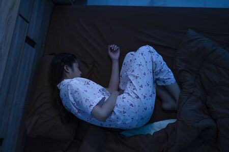 Asian woman menstrual cramps women she is in bed at nightの写真素材