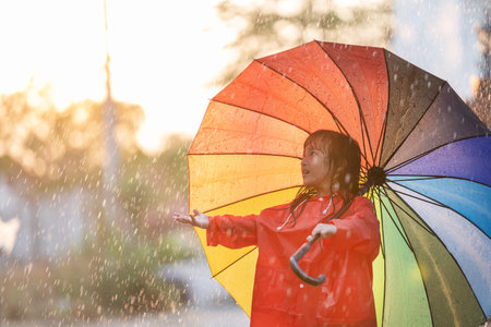 Asian children spreading umbrella to play in the rainの写真素材