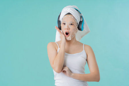 Asian woman is facial mask. she is listening to happy music and surprise.の写真素材