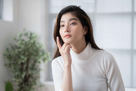 Asian woman is applying cream to her face.の写真素材