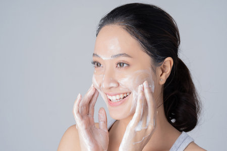 Beautiful female asian Wash face with cleansing foam. in studio
