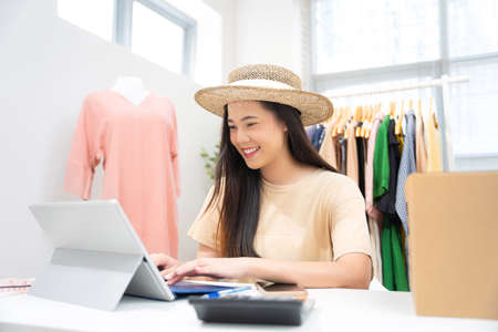 Asian woman selling vintage clothes, she is live on social media.She is answering customers questions.の写真素材