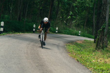 Asian men are cycling road bike in the morning.He is on a forest road.の写真素材