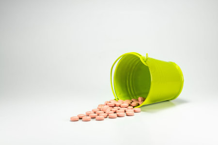 Pills, tablets in green metal bucket on white background.