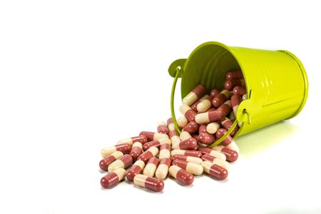 capsules in green metal bucket on white background.の写真素材