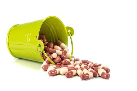 capsules in green metal bucket on white background.の写真素材