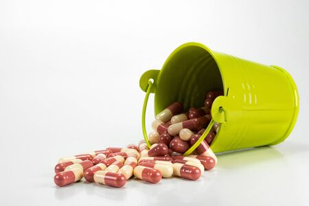 capsules in green metal bucket on white background.の写真素材