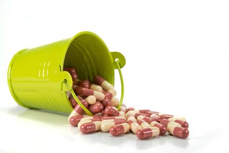 capsules in green metal bucket on white background.の写真素材