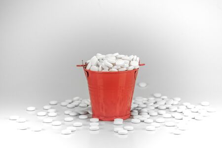 White pills, tablets in red metal bucket on white background.の写真素材