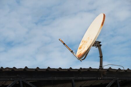 broken and old satellite dish on the roof and blue sky background.の写真素材