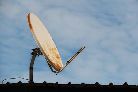 broken and old satellite dish on the roof and blue sky background.の写真素材